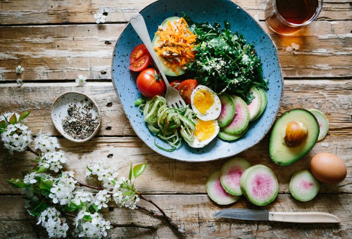 Plate of food on a rustic table with eggs, veggies and salad