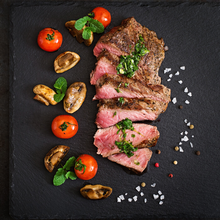 Sliced steak on a black stone tablet
