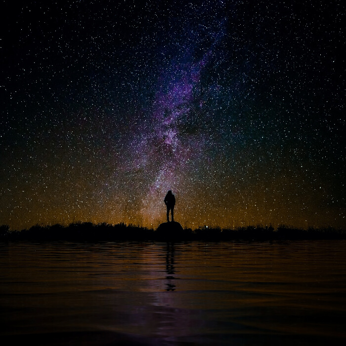Woman standing on a rock looking out to the night sky