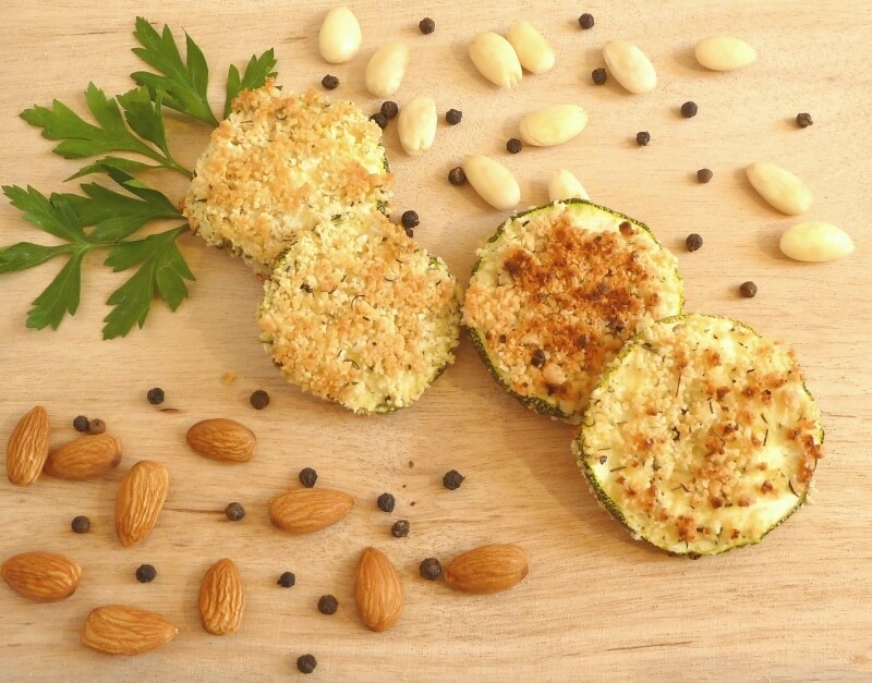 Almond breaded zucchini rounds on a wooden platter, garnished with celery