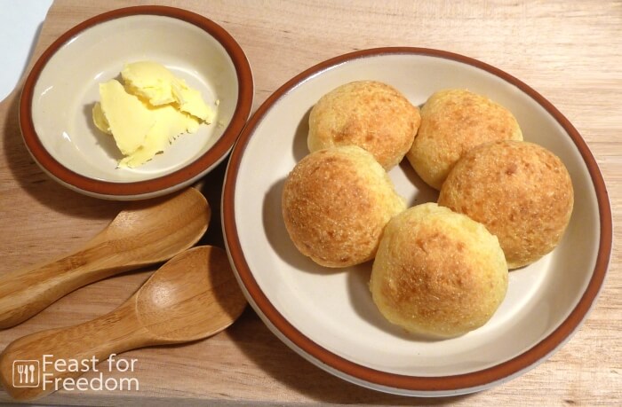 Cheese buns on a plate next to a small dish of butter