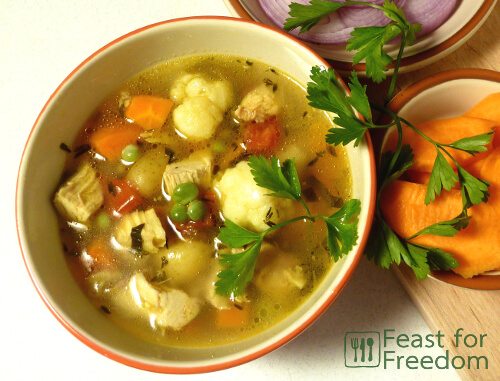 A bowl of chicken soup and garnished with parsley