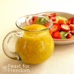 Jar of homemade fruit salad dressing beside some fruit