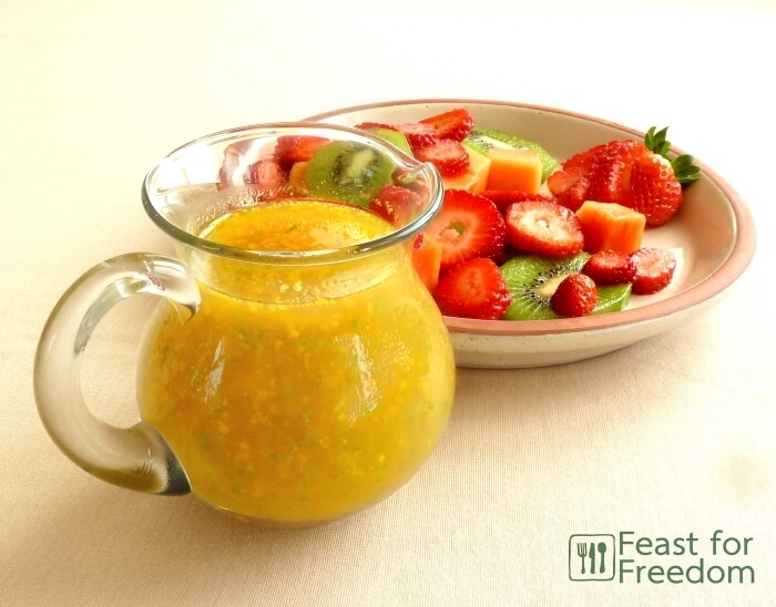 Jar of homemade fruit salad dressing beside some fruit