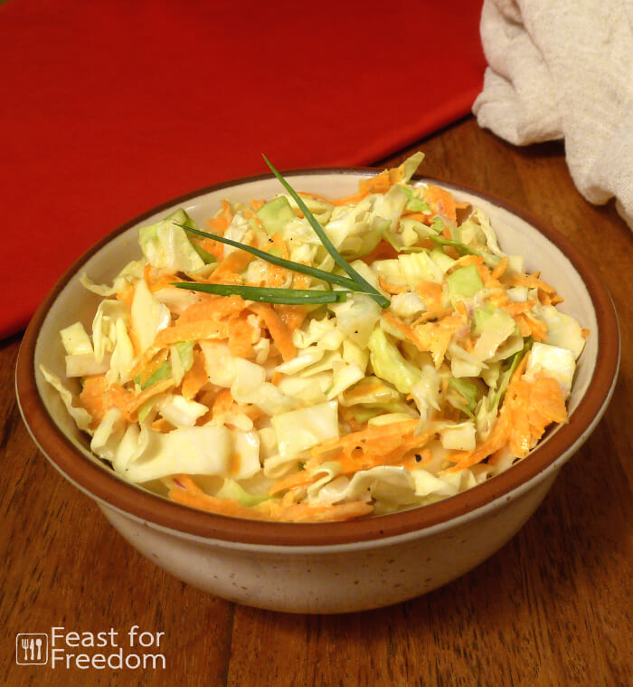 Creamy coleslaw in a bowl with a green onion garnish