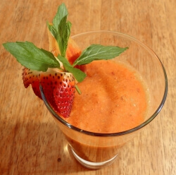 Strawberry and peach smoothie in a glass with a strawberry garnish