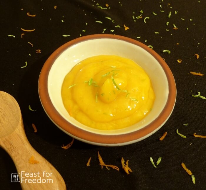 Mango sauce in a little dish sprinkled with fresh lime zest