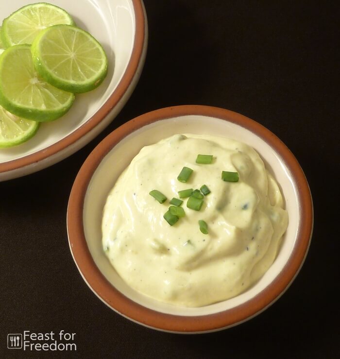 Tartar sauce in a bowl with sliced limes