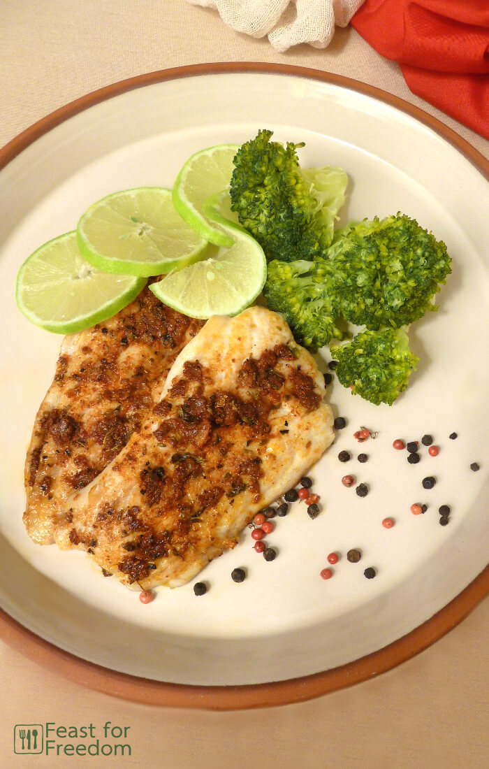 Pan fried fish with a savory spice rub with steamed broccoli and limes