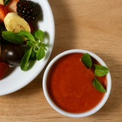 Raspberry dressing in a little dish next to a fruit salad