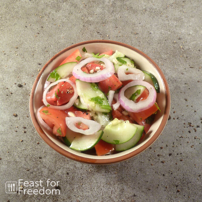 Tomato cucumber salad with red onions in a bowl
